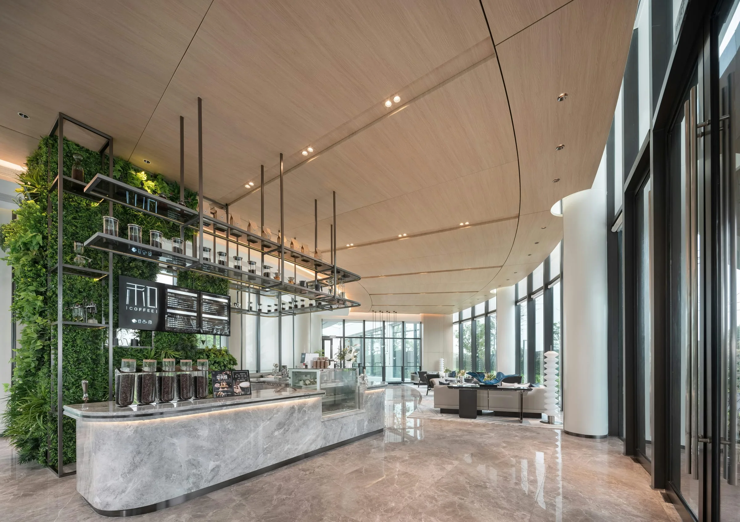 A bright lounge with a coffee bar, planted wall and sofas by tall windows